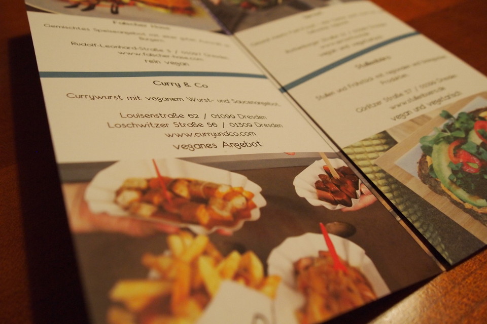 Aufgeschlagene Flyer mit Bildern und Informationen über eine Auswahl veganerfreundlicher Restaurants.